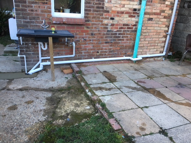 Pipe diverts rainwater down towards the new gully