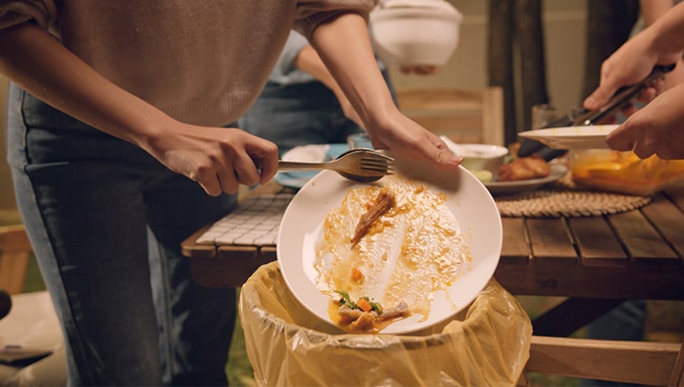 scraping plate of food into bin